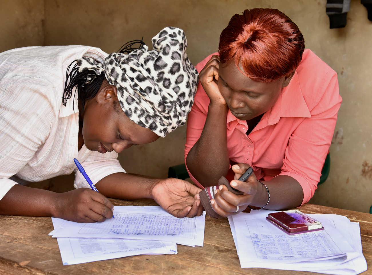 Two female coffee farmers completing paperwork in Kenya